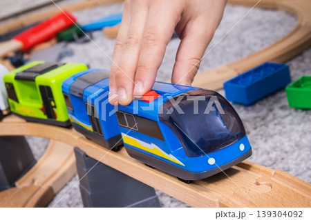 Hand of boy playing with train and wooden toy tracks. Child development and happy childhood Hand of boy playing with train and wooden toy tracks. Child development and happy childhood 139304092