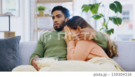 Fear, hug and couple watching tv on a sofa with popcorn for movie, film or streaming show at home. Wow, television and people embrace in living room with cinema snack for omg, horror or spooky series Fear, hug and couple watching tv on a sofa with popcorn for movie, film or streaming show at home. Wow, television and people embrace in living room with cinema snack for omg, horror or spooky series 139304316