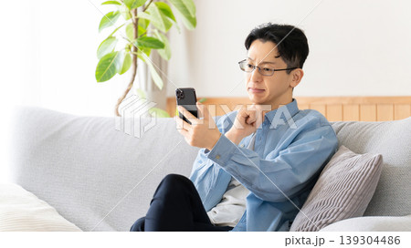 スマートフォンを見て真剣な表情で考える男性 スマートフォンを見て真剣な表情で考える男性 139304486