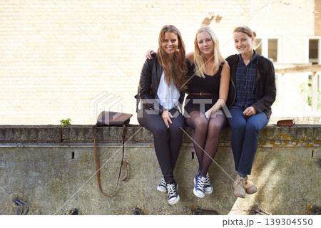 College, friends and portrait of sitting on a wall, outdoor on campus with women and happiness. Social, students and smile for learning, education and studying at academy with backpack in morning College, friends and portrait of sitting on a wall, outdoor on campus with women and happiness. Social, students and smile for learning, education and studying at academy with backpack in morning 139304550