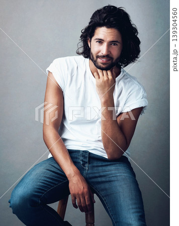 Fashion, handsome and portrait of man in studio on a stool with casual, cool and stylish outfit. Happy, smile and confident young male model from Mexico with trendy style on chair by gray background. Fashion, handsome and portrait of man in studio on a stool with casual, cool and stylish outfit. Happy, smile and confident young male model from Mexico with trendy style on chair by gray background. 139304560