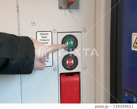 Person's finger presses green open button on train door control panel, indicating passenger access and transit operation Person's finger presses green open button on train door control panel, indicating passenger access and transit operation 139304651