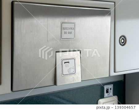 Modern stainless steel hand dryer mounted on a wall in a public restroom or train compartment, showcasing hygienic facility features for travelers Modern stainless steel hand dryer mounted on a wall in a public restroom or train compartment, showcasing hygienic facility features for travelers 139304657