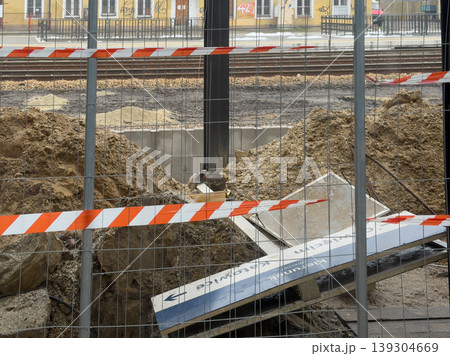 Construction site with warning tape and piles of dirt next to railway tracks, indicating urban development and infrastructure renewal project 139304669