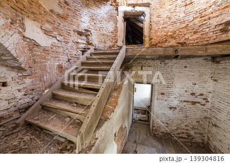 Large spacious forsaken empty basement room of ancient building or palace with cracked plastered brick walls, dirty floor and wooden staircase ladder. Large spacious forsaken empty basement room of ancient building or palace with cracked plastered brick walls, dirty floor and wooden staircase ladder. 139304816