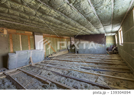 House attic under construction. Mansard walls and ceiling insulation with rock wool. Fiberglass insulation material in wooden frame for cold barrier House attic under construction. Mansard walls and ceiling insulation with rock wool. Fiberglass insulation material in wooden frame for cold barrier 139304894