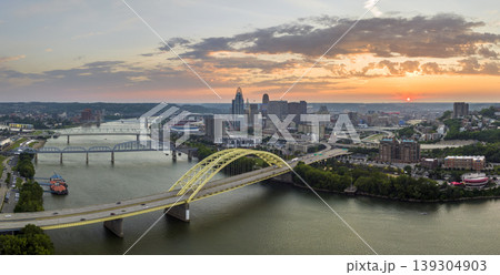 Highway traffic in Cincinnati, Ohio on Daniel Carter Beard Bridge with brightly illuminated high skyscraper buildings in downtown district. American city with business financial district at sunset Highway traffic in Cincinnati, Ohio on Daniel Carter Beard Bridge with brightly illuminated high skyscraper buildings in downtown district. American city with business financial district at sunset 139304903