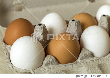 Hen eggs in open cardboard egg carton on kitchen table light copy space background. Healthy organic food and diet concept. Hen eggs in open cardboard egg carton on kitchen table light copy space background. Healthy organic food and diet concept. 139304923