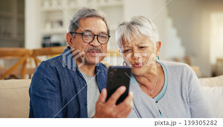 Senior couple, smartphone and video call in living room sofa, conversation and joyful. Grandparents, technology and communication with family, man and woman in retirement, happy and connection 139305282