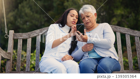Phone, senior or mother with woman on bench in nature reading news on social media in retirement. Online gossip, mature parent or daughter for together in park or garden as a family with mobile app Phone, senior or mother with woman on bench in nature reading news on social media in retirement. Online gossip, mature parent or daughter for together in park or garden as a family with mobile app 139305364