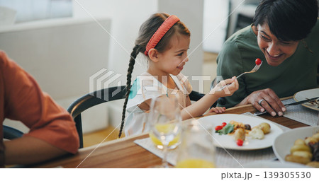 Food, family and a girl feeding her grandmother at a dining room table while in their home for a visit together. Love, smile and a senior woman eating a meal with her happy grandchild in an apartment 139305530