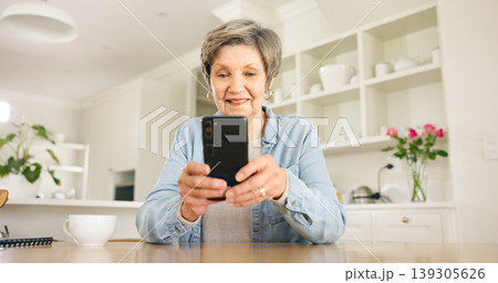 Happy senior woman, phone and social media in relax for communication or networking in kitchen at home. Mature female person smile on mobile smartphone for online chatting, texting or search at house Happy senior woman, phone and social media in relax for communication or networking in kitchen at home. Mature female person smile on mobile smartphone for online chatting, texting or search at house 139305626