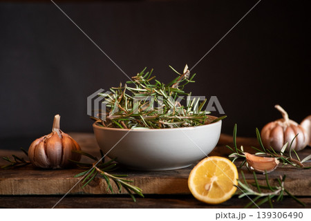 Fresh Rosemary Sprigs with Garlic and Lemon on Wooden Cutting Board Fresh Rosemary Sprigs with Garlic and Lemon on Wooden Cutting Board 139306490