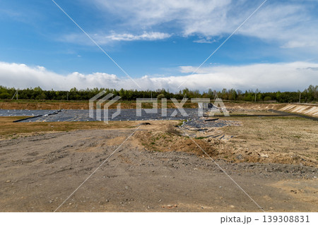 Construction work is in progress at a new landfill site with covered areas and an open landscape during daytime under a blue sky 139308831