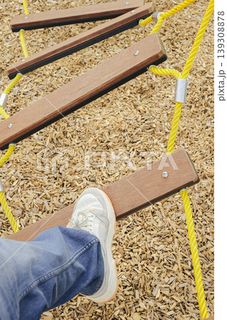 Person foot stepping on a wooden balance plank in a playground. Childishness und playful movement. Person foot stepping on a wooden balance plank in a playground. Childishness und playful movement. 139308878