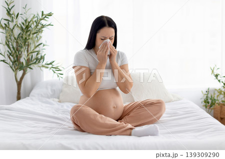 Pregnant woman sneezing into tissue, illustrating cold symptoms, immunity challenges during pregnancy Pregnant woman sneezing into tissue, illustrating cold symptoms, immunity challenges during pregnancy 139309290