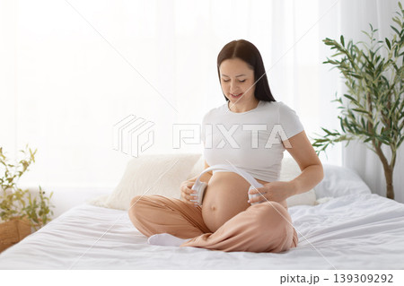 Pregnant woman placing headphones on belly, representing prenatal bonding through music Pregnant woman placing headphones on belly, representing prenatal bonding through music 139309292