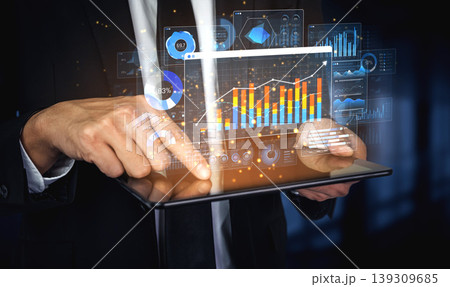 A businessman interacts with a digital tablet showcasing vibrant graphs and charts, symbolizing modern data analysis in finance and technology in a professional environment. Sigmoid A businessman interacts with a digital tablet showcasing vibrant graphs and charts, symbolizing modern data analysis in finance and technology in a professional environment. Sigmoid 139309685