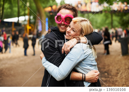 Happy couple, hug and outdoor festival for love, care or support at crowded party, DJ event or music park. Man and woman smile in embrace, affection or trust for festive celebration or summer break Happy couple, hug and outdoor festival for love, care or support at crowded party, DJ event or music park. Man and woman smile in embrace, affection or trust for festive celebration or summer break 139310108