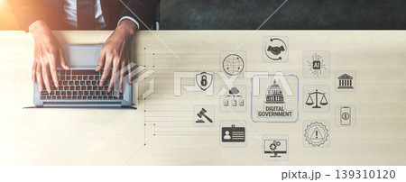 Hands of a Business Professional Typing on a Laptop with Digital Government Icons, Symbols of Technology, Law, Security, and Administration on the Desk Fluxor Hands of a Business Professional Typing on a Laptop with Digital Government Icons, Symbols of Technology, Law, Security, and Administration on the Desk Fluxor 139310120