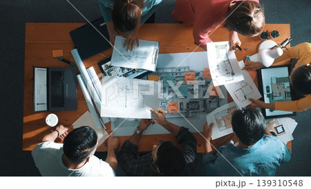 Top view of engineer team holding blueprint and standing at table. Symposium. Top view of engineer team holding blueprint and standing at table. Symposium. 139310548
