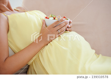 Pregnant woman, eating salad and living room couch, alone and enjoying delicious pregnancy craving. Relaxed, vegetables and maternity wellness with healthy food meal and nutrition satisfaction Pregnant woman, eating salad and living room couch, alone and enjoying delicious pregnancy craving. Relaxed, vegetables and maternity wellness with healthy food meal and nutrition satisfaction 139310578