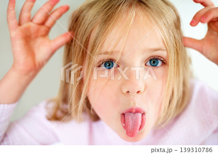 Silly, tongue out and portrait of child in home with funny, comic and humor facial expression. Childhood, crazy and closeup of young girl with hand gesture for goofy face, playful joke and emoji Silly, tongue out and portrait of child in home with funny, comic and humor facial expression. Childhood, crazy and closeup of young girl with hand gesture for goofy face, playful joke and emoji 139310786