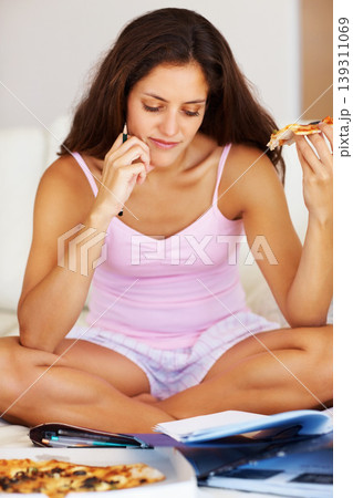 Studying, eating and woman in bedroom with pizza for dinner, lunch or supper reading documents. Paperwork, textbook and young female student enjoy fast food and preparing for test, exam or assignment 139311069