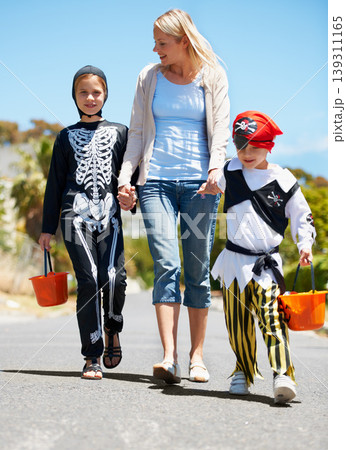 Mother, children and holding hands with Halloween costume, fun and playing with joy, cheerful or love. Outdoor, mama or kids with fantasy outfit, happiness or walking with a smile or family in street 139311165