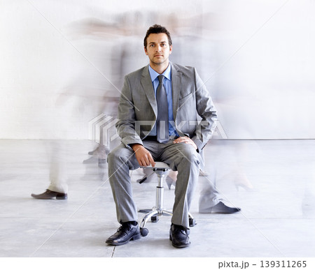 Portrait, chair and a corporate man in a busy office with motion blur people walking for company productivity. Work, business and professional with a young employee in a suit sitting in the workplace Portrait, chair and a corporate man in a busy office with motion blur people walking for company productivity. Work, business and professional with a young employee in a suit sitting in the workplace 139311265