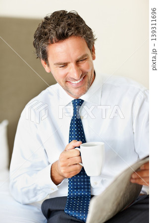 Businessman, face and happy with coffee or newspaper in bedroom of home for morning routine and news. Entrepreneur, person and reading with article, cappuccino or espresso for story and information 139311696