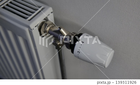 Thermostatic radiator valve on a white heating unit 139311926