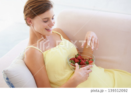 Pregnant woman, eating strawberries and happy in home, alone and enjoying delicious pregnancy craving. Good mood, fruit and maternity wellness with healthy food snack and nutrition satisfaction Pregnant woman, eating strawberries and happy in home, alone and enjoying delicious pregnancy craving. Good mood, fruit and maternity wellness with healthy food snack and nutrition satisfaction 139312092