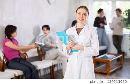 Young female nurse inviting patients in clinic 139313420