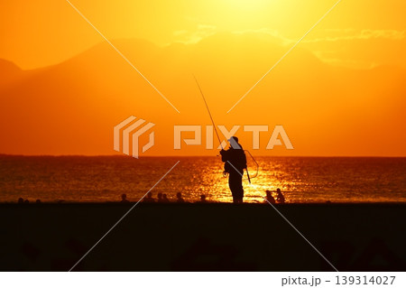 夕暮れの海で釣りを楽しむ人のシルエットと美しい夕景 夕暮れの海で釣りを楽しむ人のシルエットと美しい夕景 139314027