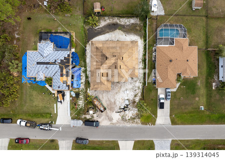 Construction workers laying asphalt shingles on rooftop. Private house roof covering underway. Florida home building project. Construction workers laying asphalt shingles on rooftop. Private house roof covering underway. Florida home building project. 139314045
