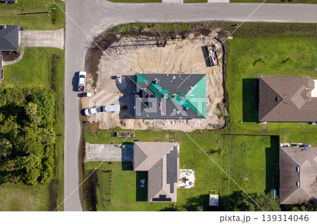 Construction workers installing asphalt shingles on residential home. New house rooftop being built. Construction workers installing asphalt shingles on residential home. New house rooftop being built. 139314046