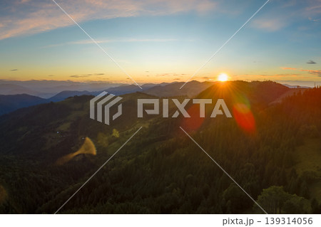 Colorful sunset in wild mountains. Dark pine forest illuminated with bright setting sun. Beautiful nature landscape 139314056