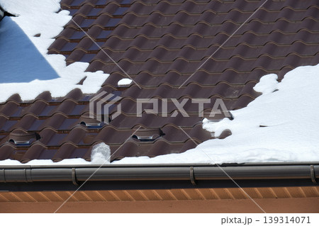 Closeup of house roof top covered with snow in cold winter. Tiled covering of building in wintertime weather 139314071