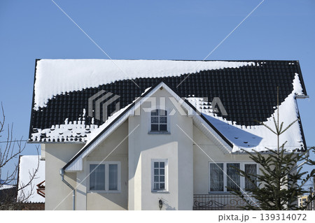 Closeup of house roof top covered with snow in cold winter. Tiled covering of building in wintertime weather Closeup of house roof top covered with snow in cold winter. Tiled covering of building in wintertime weather 139314072