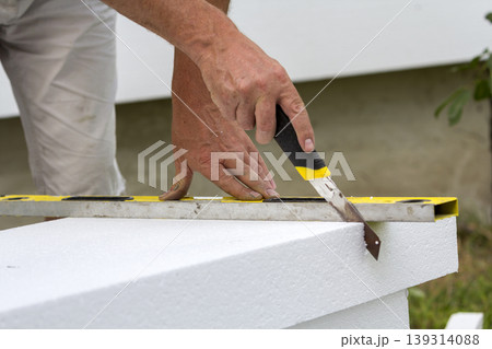 Close-up of worker hand with knife and level cutting white rigid polyurethane foam sheet for house insulation. Modern technology, renovation, professional job, alternative for mineral wool concept. 139314088