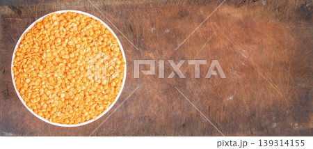 Bowl of uncooked dhal on wooden board Bowl of uncooked dhal on wooden board 139314155