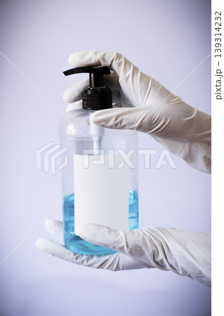 Presenting sanitizer bottle by both hands with medical latex gloves Presenting sanitizer bottle by both hands with medical latex gloves 139314232