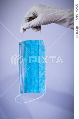 Medical face mask holding downside by gloved hand 139314235