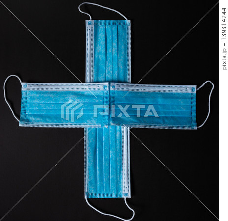 Four surgical face masks put together as a cross in black background Four surgical face masks put together as a cross in black background 139314244