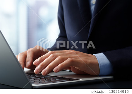 オフィスのデスクでノートパソコンを使うビジネスパーソン。手とキーボードのクローズアップ。ビジネスでの 139314916