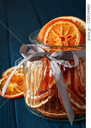 Dried orange slices arranged in a glass jar with a ribbon 139314960