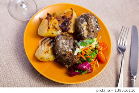 Pork cheek served with potatoes and vegetable salad 139316116