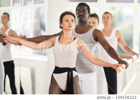 Woman mastering second ballet position at barre in choreographic studio Woman mastering second ballet position at barre in choreographic studio 139316123