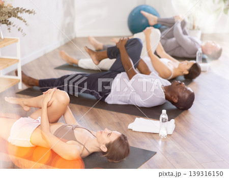 Portrait of young sporty woman having yoga class with group at sports club 139316150